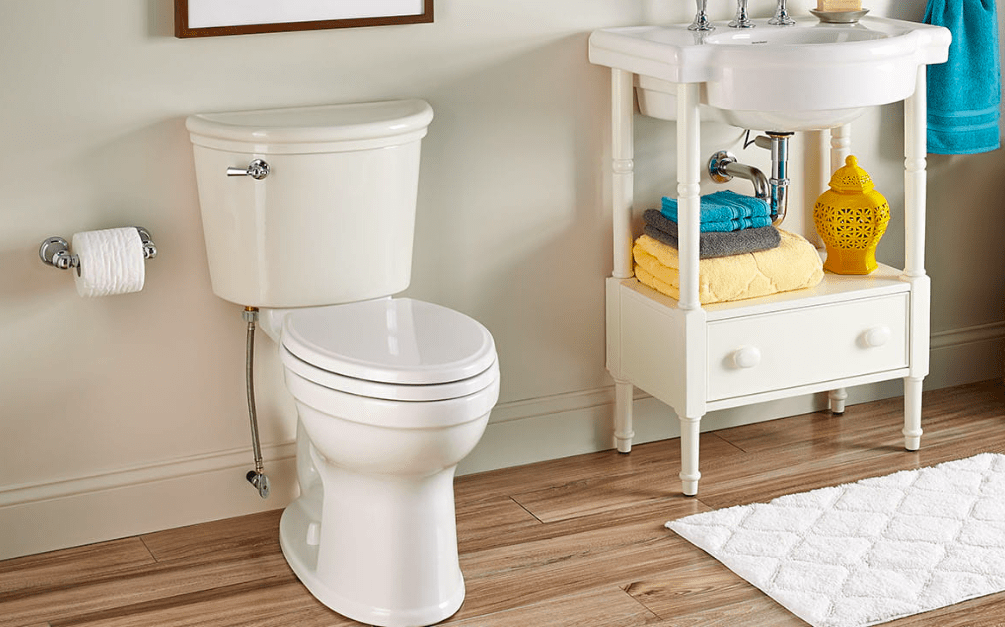 White toilet next to a sink shelving unit in a neat, clean bathroom.